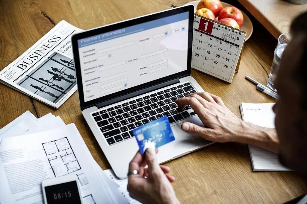 Payment operations workspace with a laptop, tablet, and planning notes